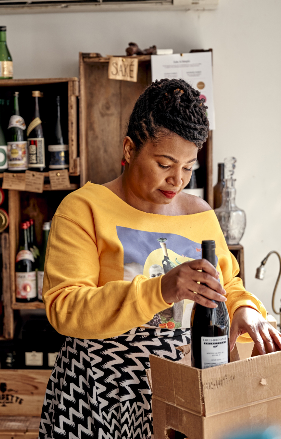 A woman in a wine shop packing a wine in a box.